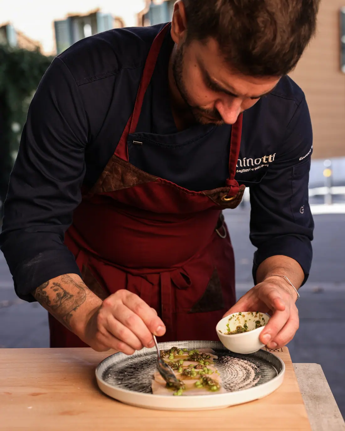 Lo chef Edoardo Minotti impiatta una salsa verde su un piatto decorato