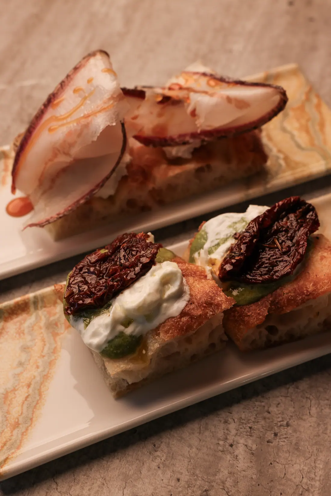 Focaccine della Bottega con stracciatella, pomodoro secco e fette di salume su piatto in onice